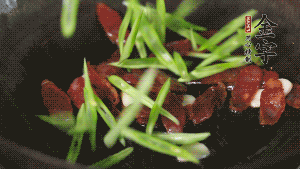 先后下香腸片、四季豆絲均勻翻炒，加適量清水燜煮一下。