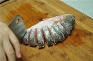 將鱸魚(yú)清洗干凈，從脊椎處切斷至腹部，腹部保留1cm左右不要切斷。