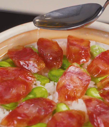 大米出現(xiàn)小孔時(shí)開(kāi)蓋放香腸，往鍋邊淋入少許油，再燜煮8~10分鐘左右。