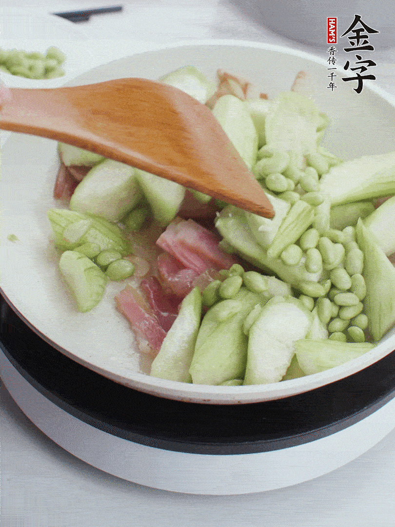 依次下絲瓜、青豆翻炒，炒至絲瓜打蔫縮小。
