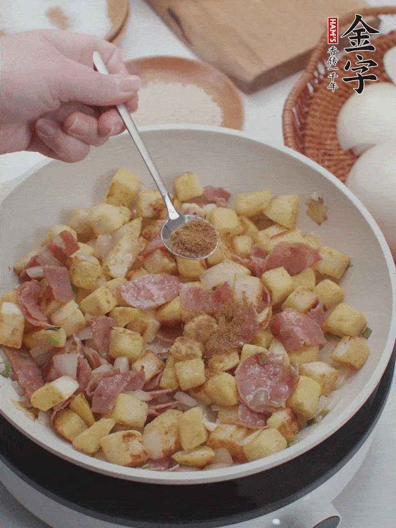 起鍋少油，煸香洋蔥丁、蔥白，加入金字培根火腿翻炒幾下，再加入饅頭丁、1小勺孜然粉、少許鹽翻炒均勻并鋪平。