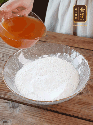 轉(zhuǎn)化糖漿、枧水、花生油攪拌均勻，加入面粉混合，醒發(fā)2小時(shí)。捏成23g一個(gè)的小球